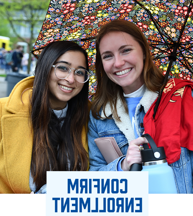 UA students under an umbrella smiling